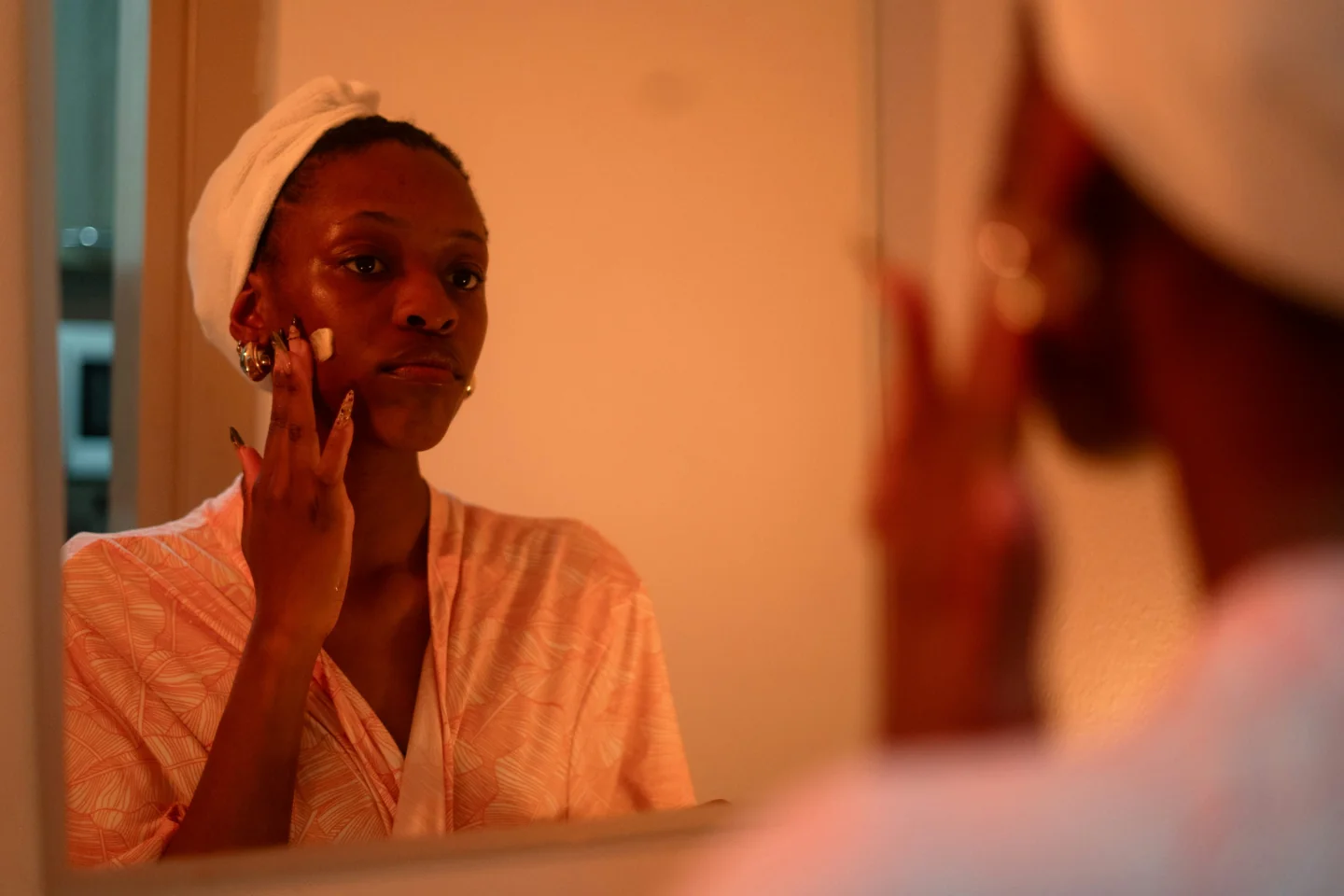 Photograph of a woman applying cream at a mirror