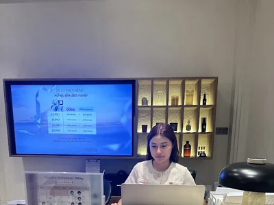 A person behind a reception counter using a laptop.