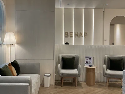 Clinic lounge with grey seating, green cushions and a BEHAP wall sign.