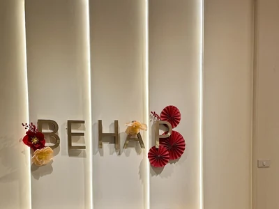 BEHAP wall sign decorated with red and yellow paper flowers.